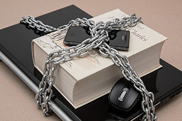 Un ordenador, un libro y un smartphone empaquetados con una cadena